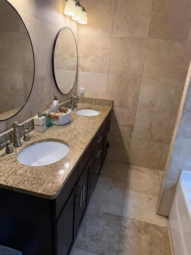 Clean double vanity with granite countertop and round mirrors