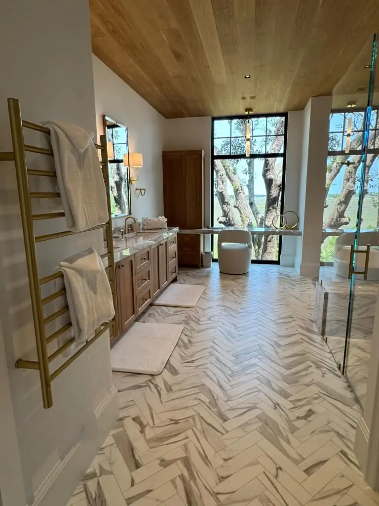 Clean bathroom with marble floor, wood vanity and folded towels